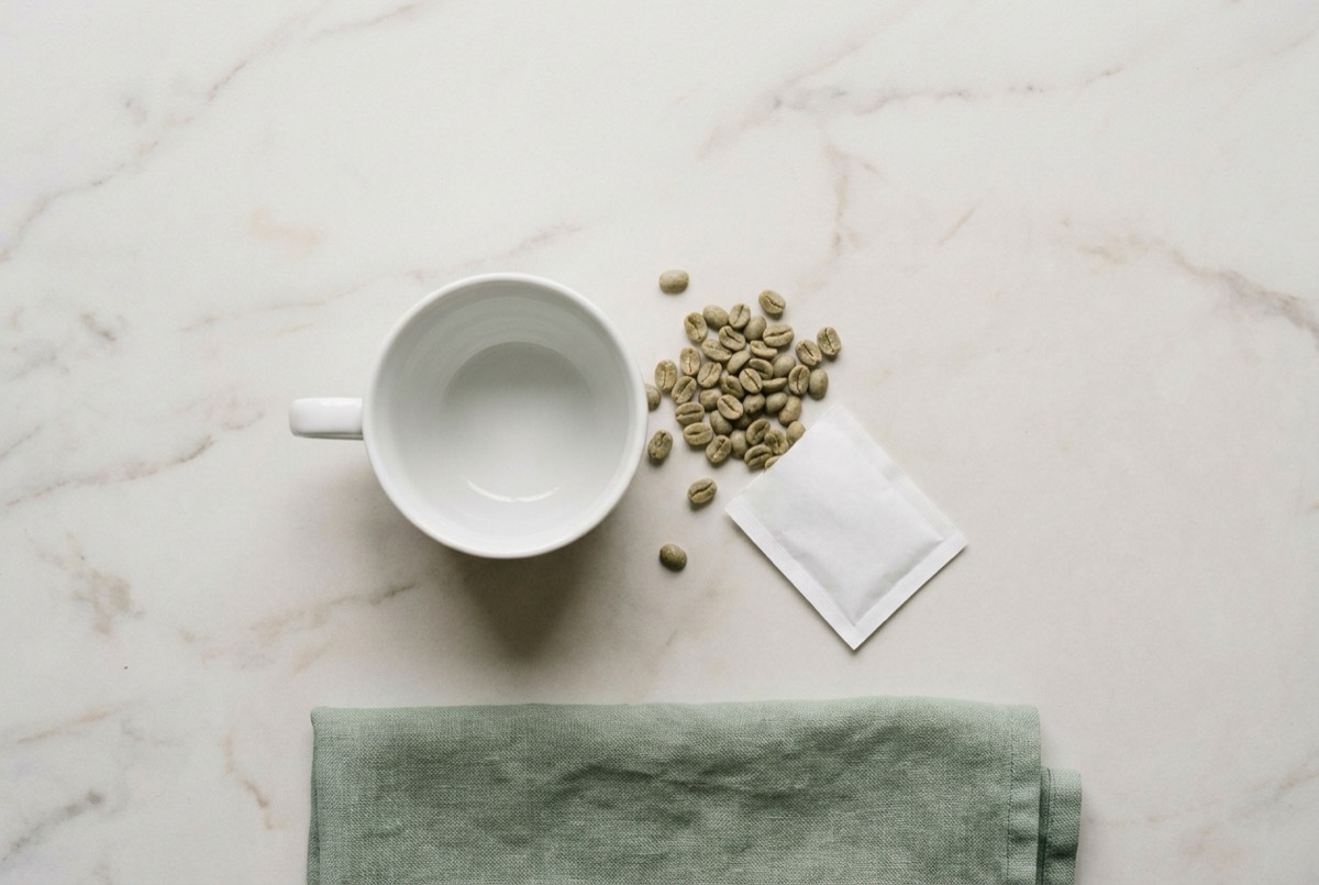 Coffee cup with green coffee beans and a sachet